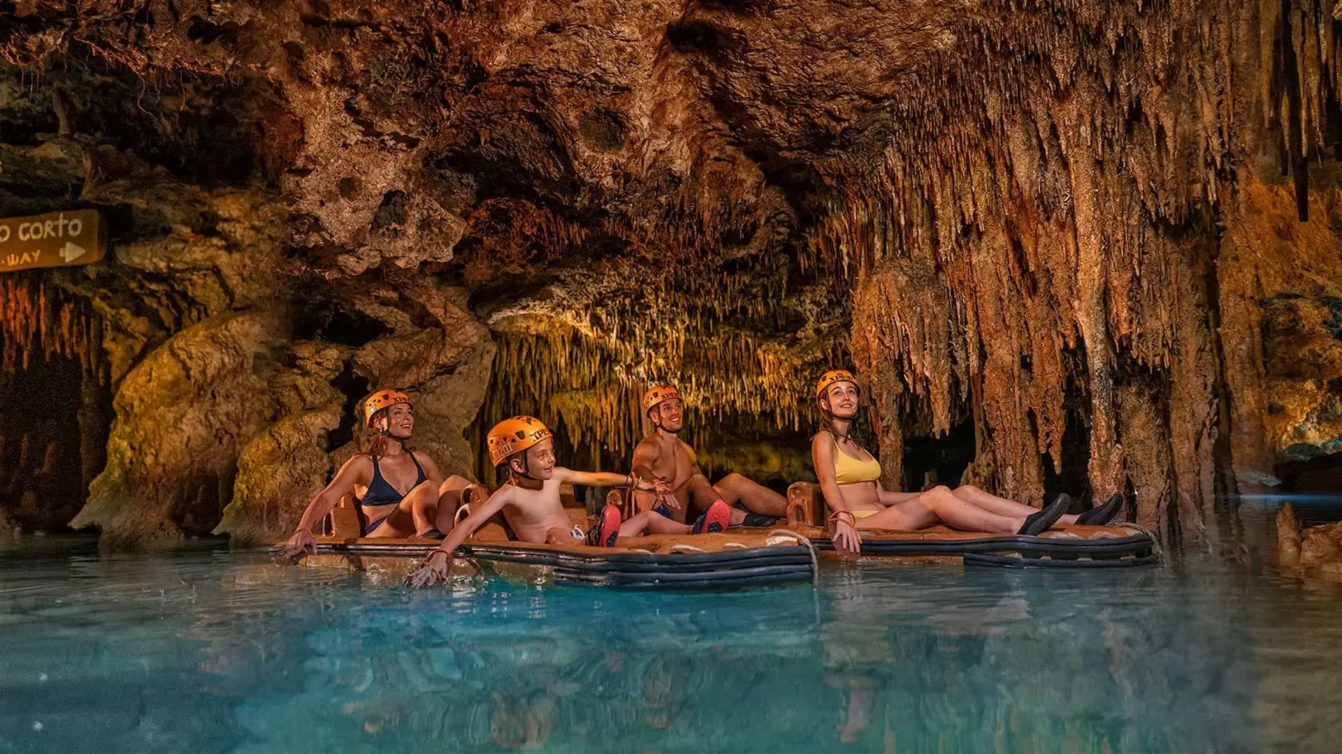 Familia recorriendo un río subterráneo en balsas dentro de Xplor