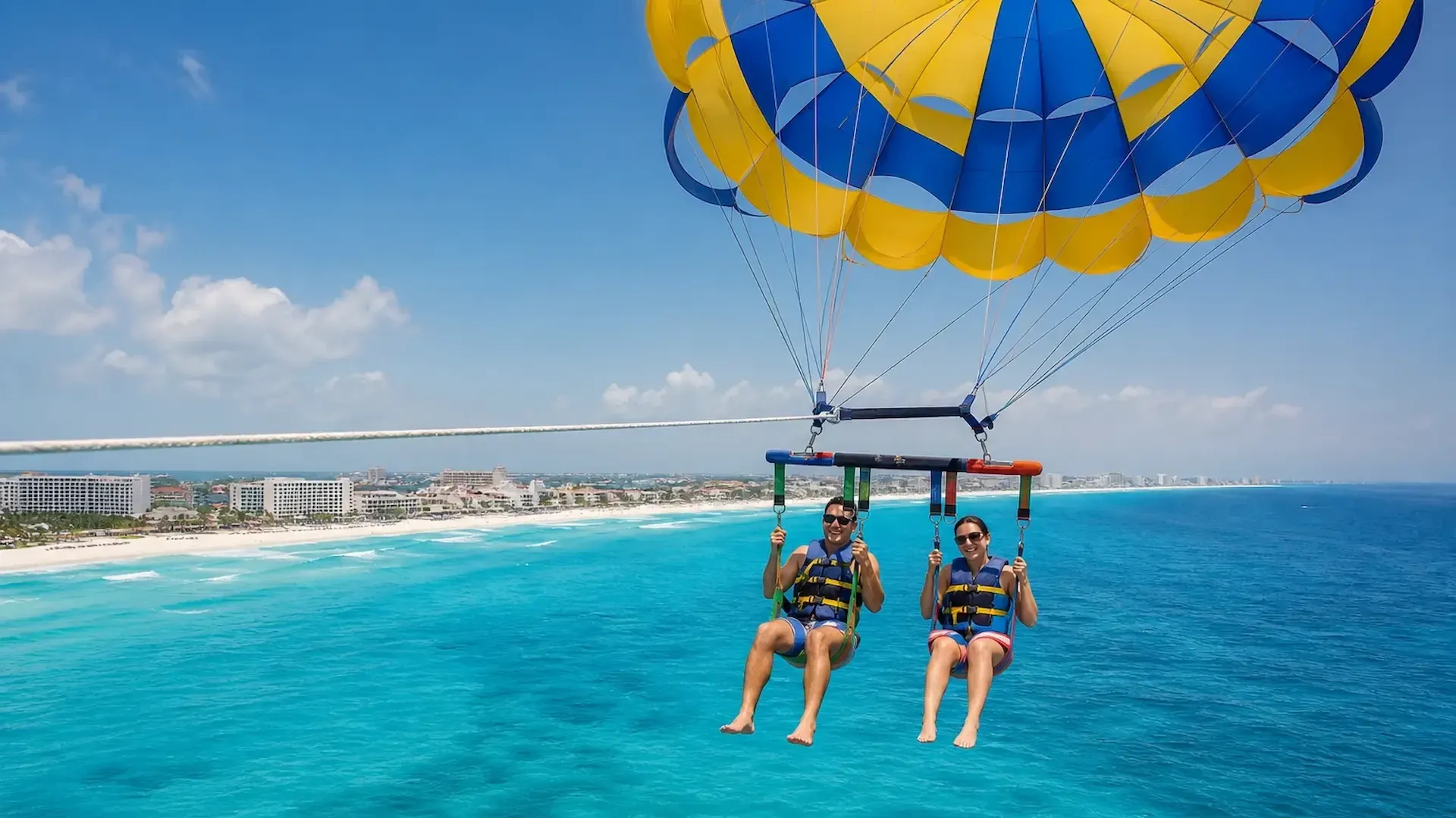 Dos personas practicando parasailing frente a la zona hotelera de Cancún