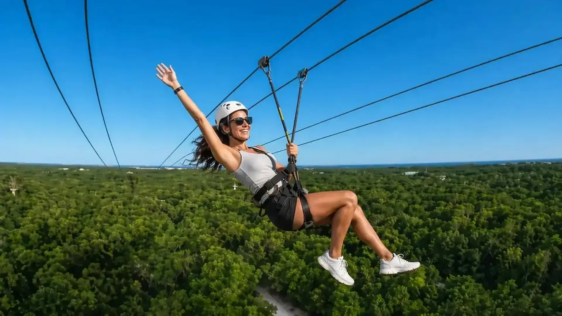 Persona deslizándose en tirolesa sobre la selva de Xplor durante el día