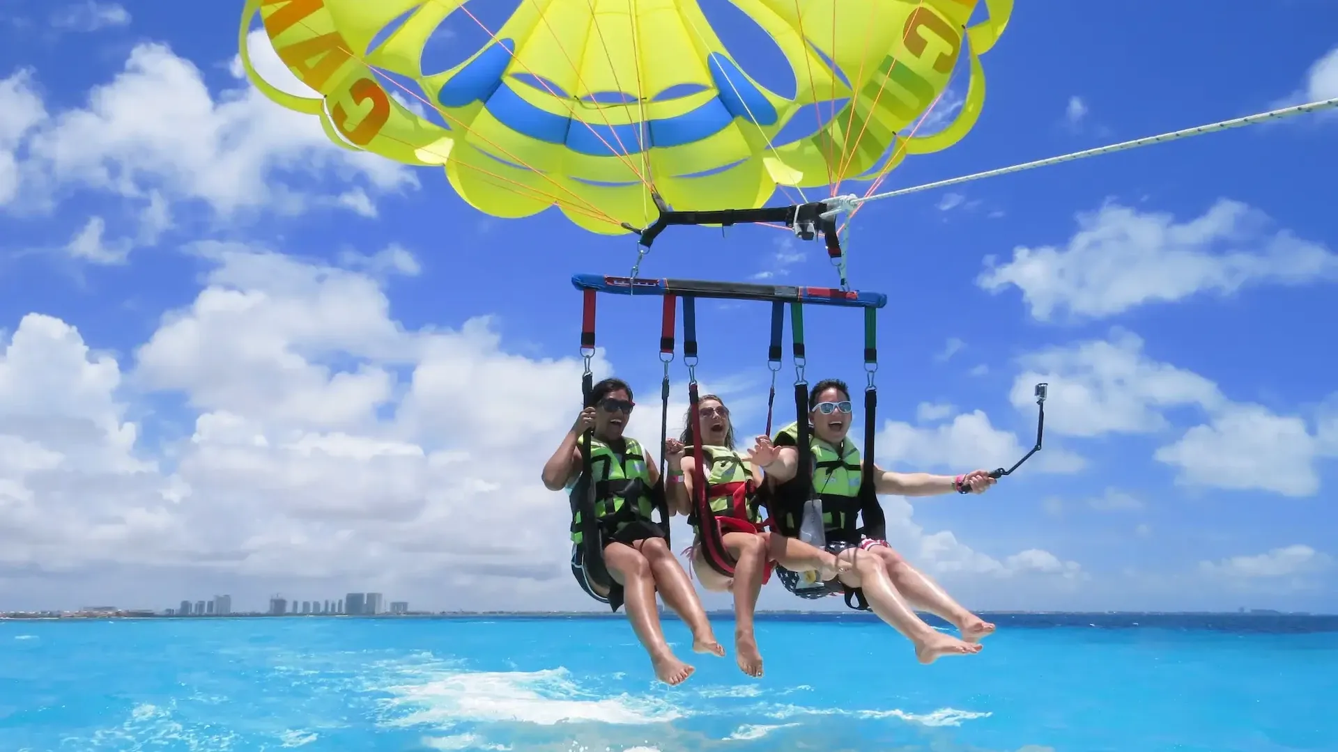 Tres personas practicando parasailing sobre el mar de Cancún