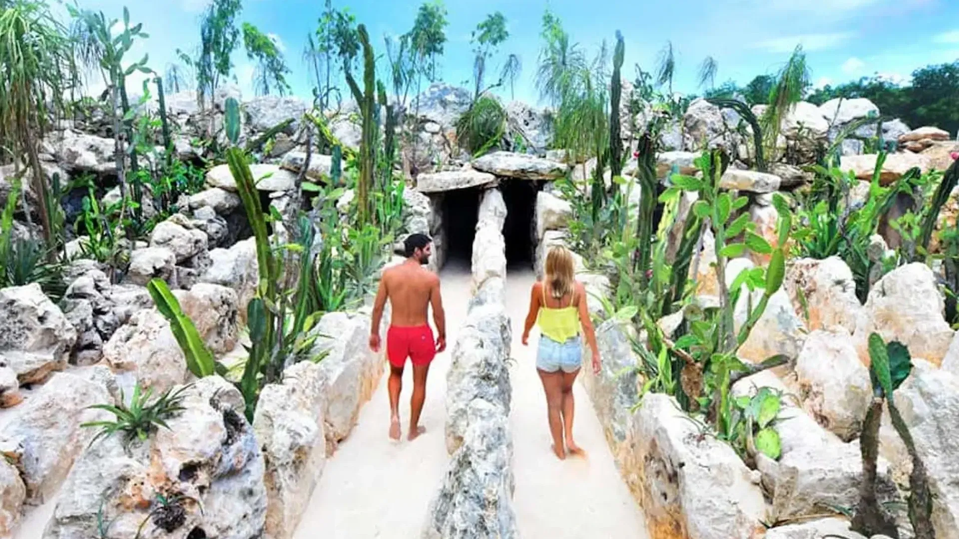 Pareja caminando entre cactus y formaciones rocosas a la entrada del Xensatorium