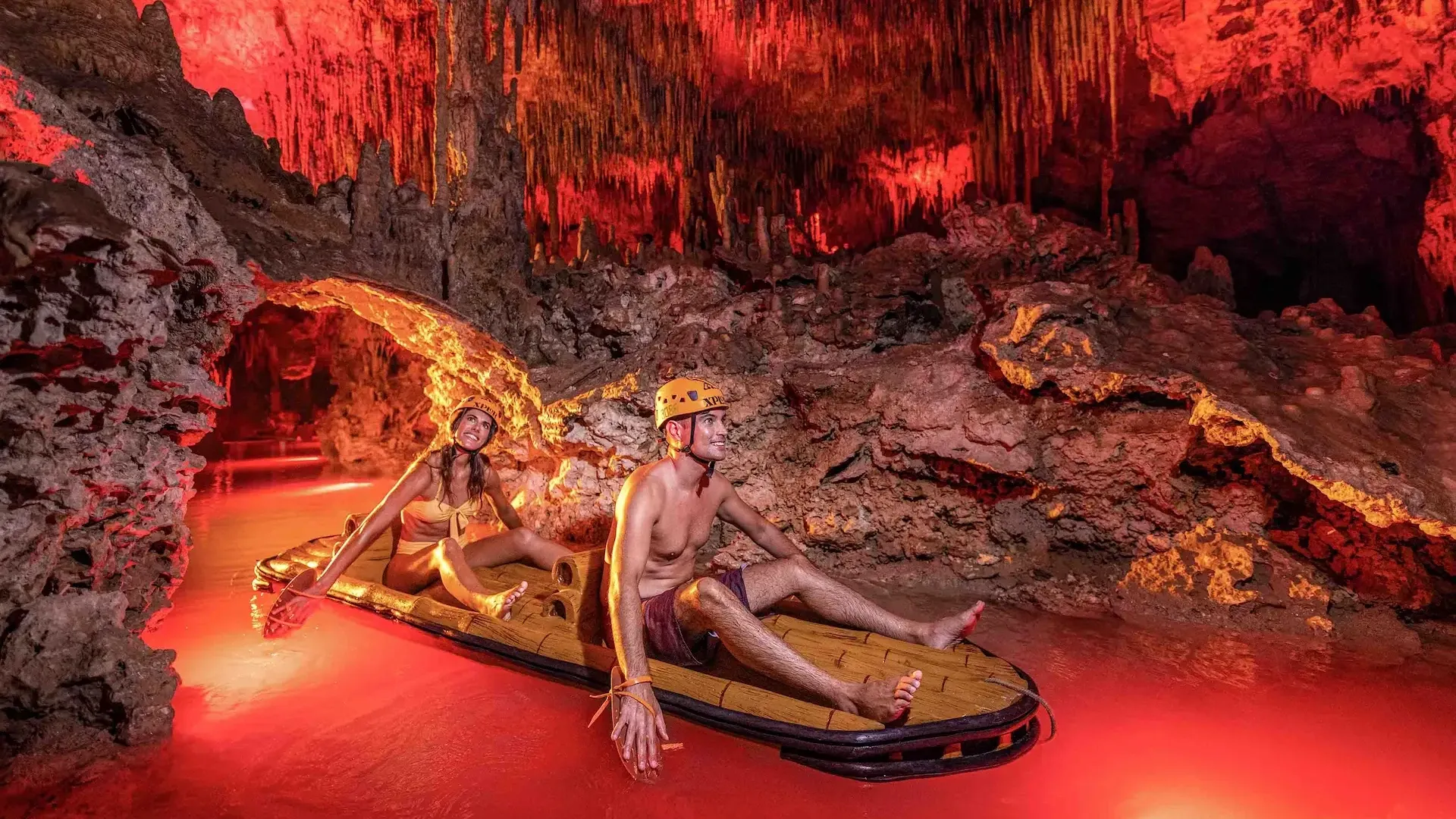 Pareja remando en balsas por una caverna iluminada de Xplor Fuego